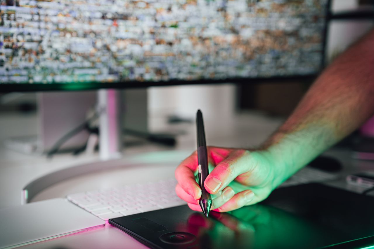 Home A digital artist using a graphics tablet and stylus in a modern workspace. High-tech creative process.