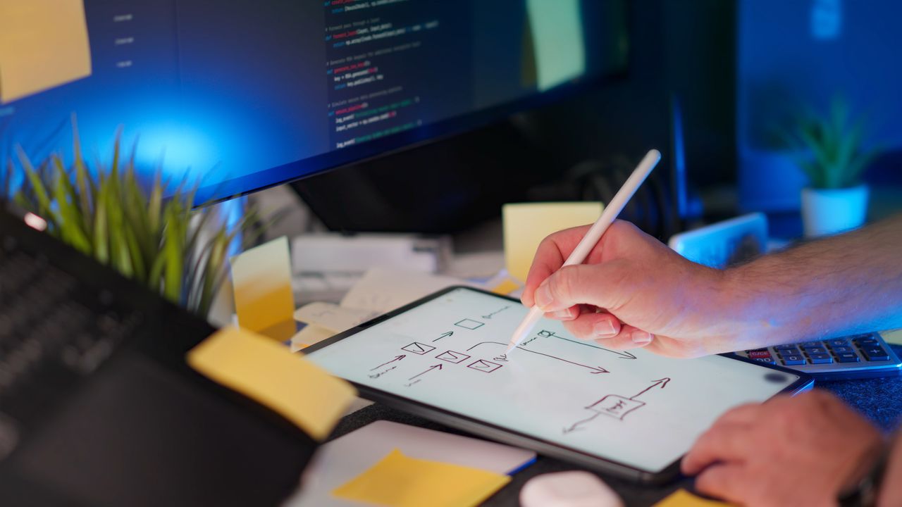 Home A vibrant workspace featuring digital sketching on a tablet and code on a monitor, showcasing a tech-savvy environment.
