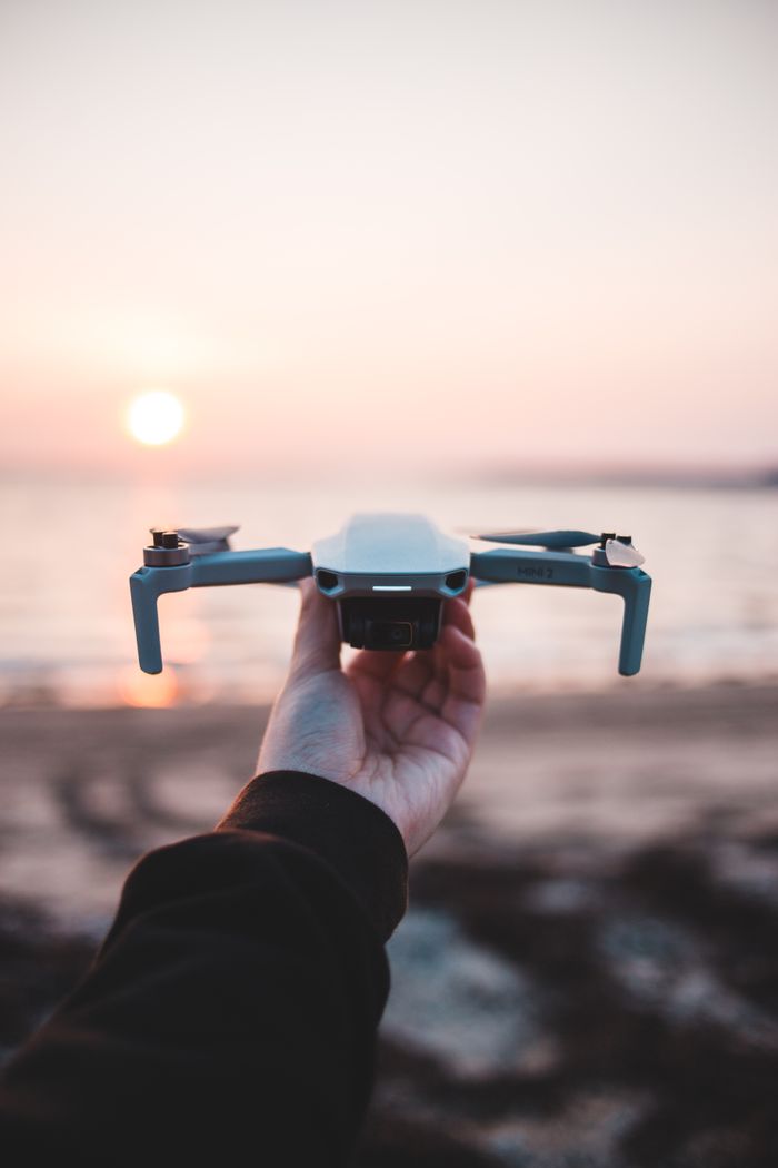 Home Close-up of a hand holding a drone at the beach during sunset.